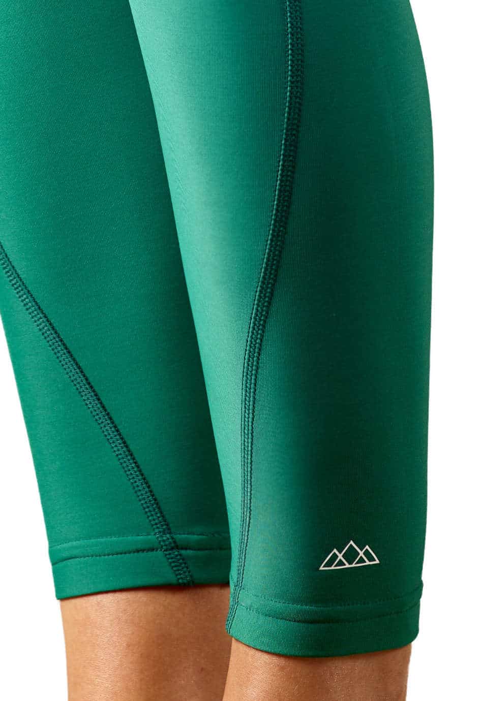 Nahaufnahme des unteren Beins der M23 Lina Leggings in Evergreen-Gruen aus nachhaltiger Bio-Baumwolle – umweltfreundlicher Stoff mit sichtbaren Nähten und aufgedrucktem Berg-Logo