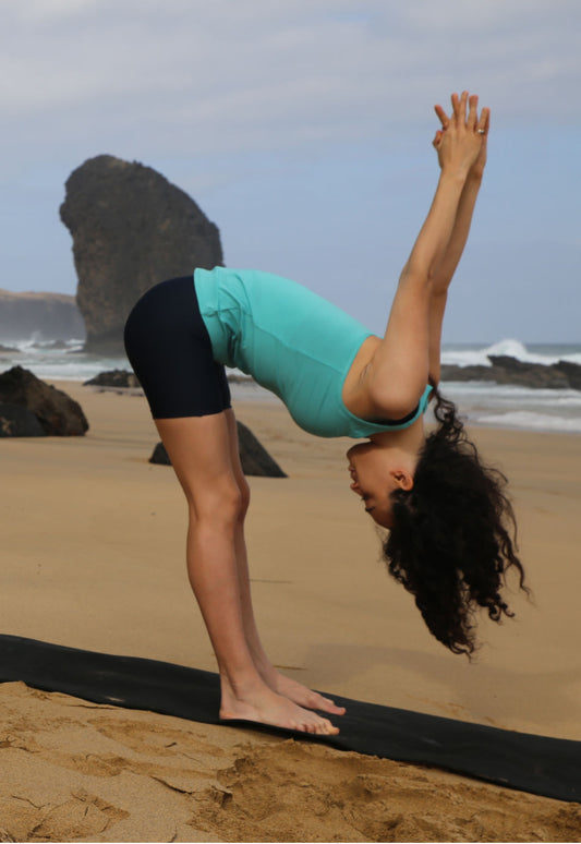 Frau beim Yoga in M23 Sue Biker-Shorts in Salute Blau aus nachhaltiger Bio-Baumwolle am Sandstrand.