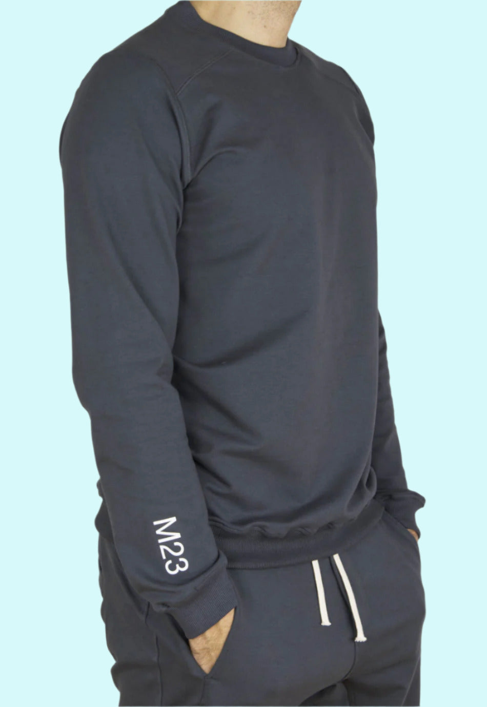 Seitenansicht des M23 Sweatshirts „Phil“ in Anthrazit aus nachhaltiger Bio-Baumwolle mit weißem M23-Print am Aermel – umweltfreundliche Herrenmode.
