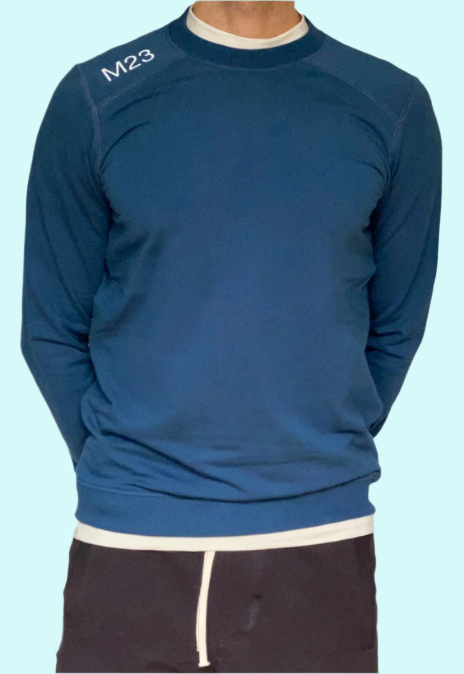 Mann traegt das M23 Sweatshirt „Phil“ in Marineblau aus nachhaltiger Bio-Baumwolle mit aufgedrucktem M23-Schriftzug – umweltfreundliche faire Mode.