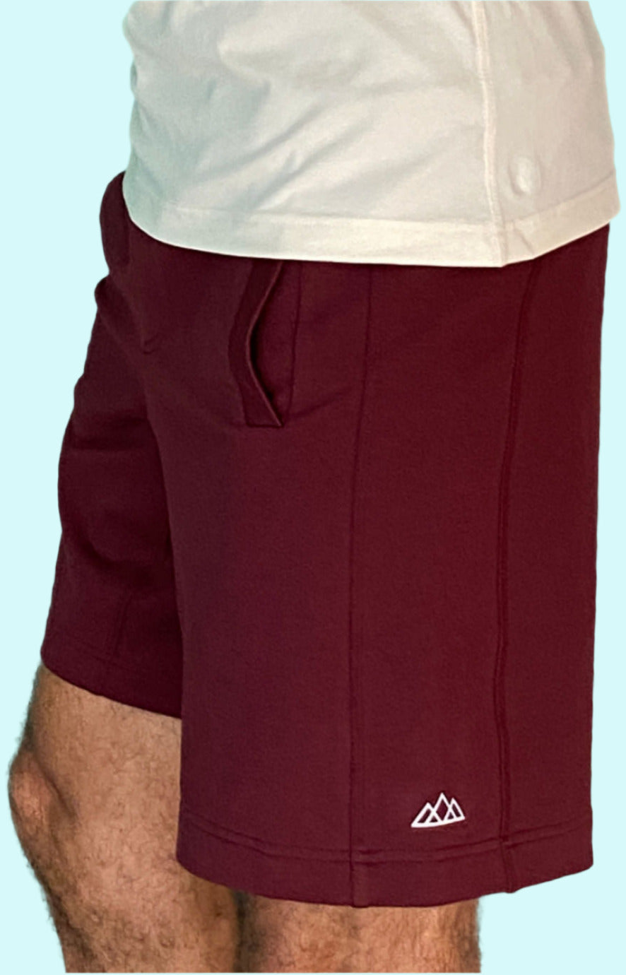 Linke Seitenansicht der M23 Zane Shorts in Bordeauxrot aus nachhaltiger Bio-Baumwolle – umweltfreundliche Herrenshorts mit klaren Nähten und gesticktem Logo