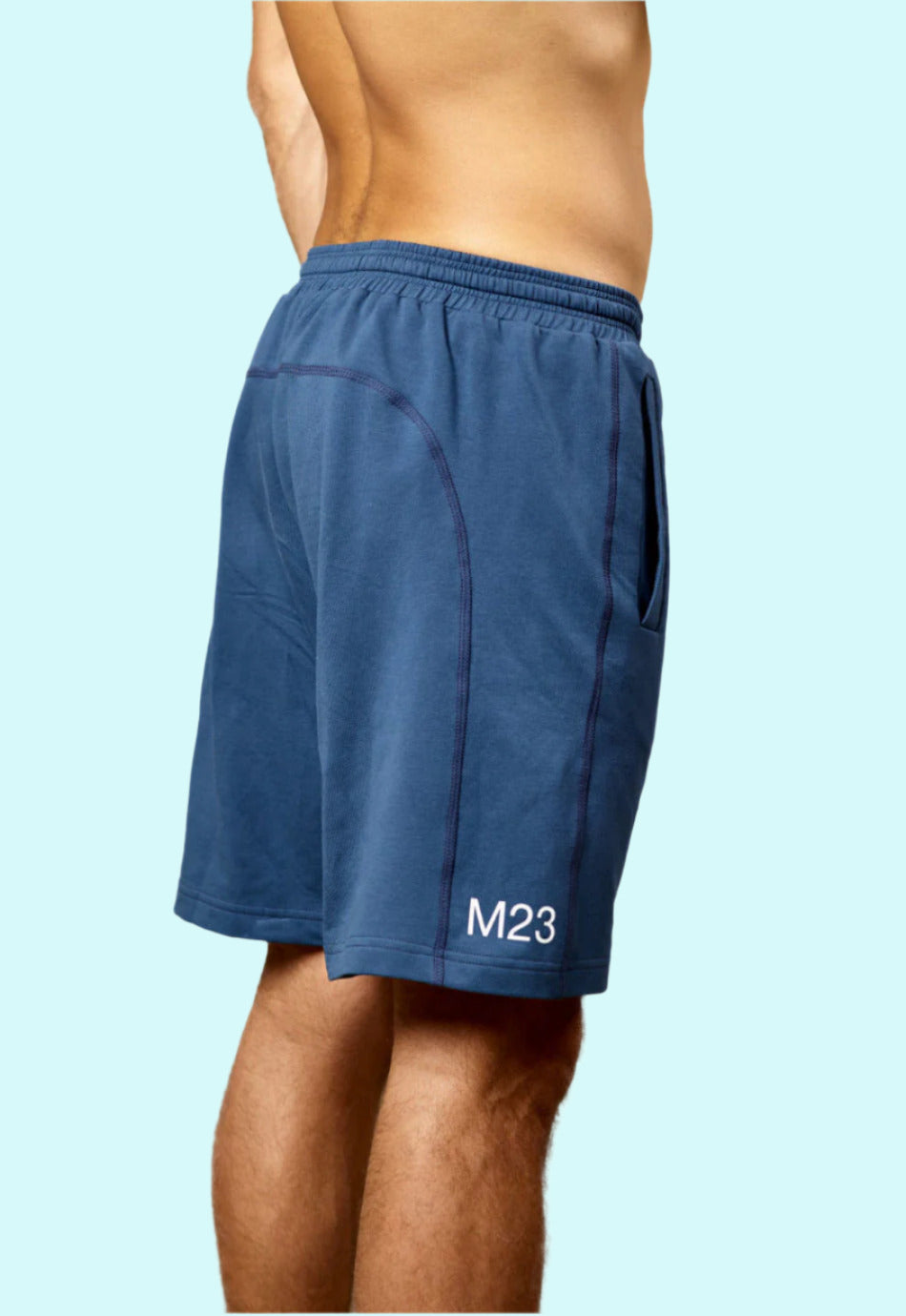 Seitenansicht eines Mannes mit M23 Zane Shorts in Marineblau aus nachhaltiger Bio-Baumwolle – umweltfreundliche Sportbekleidung