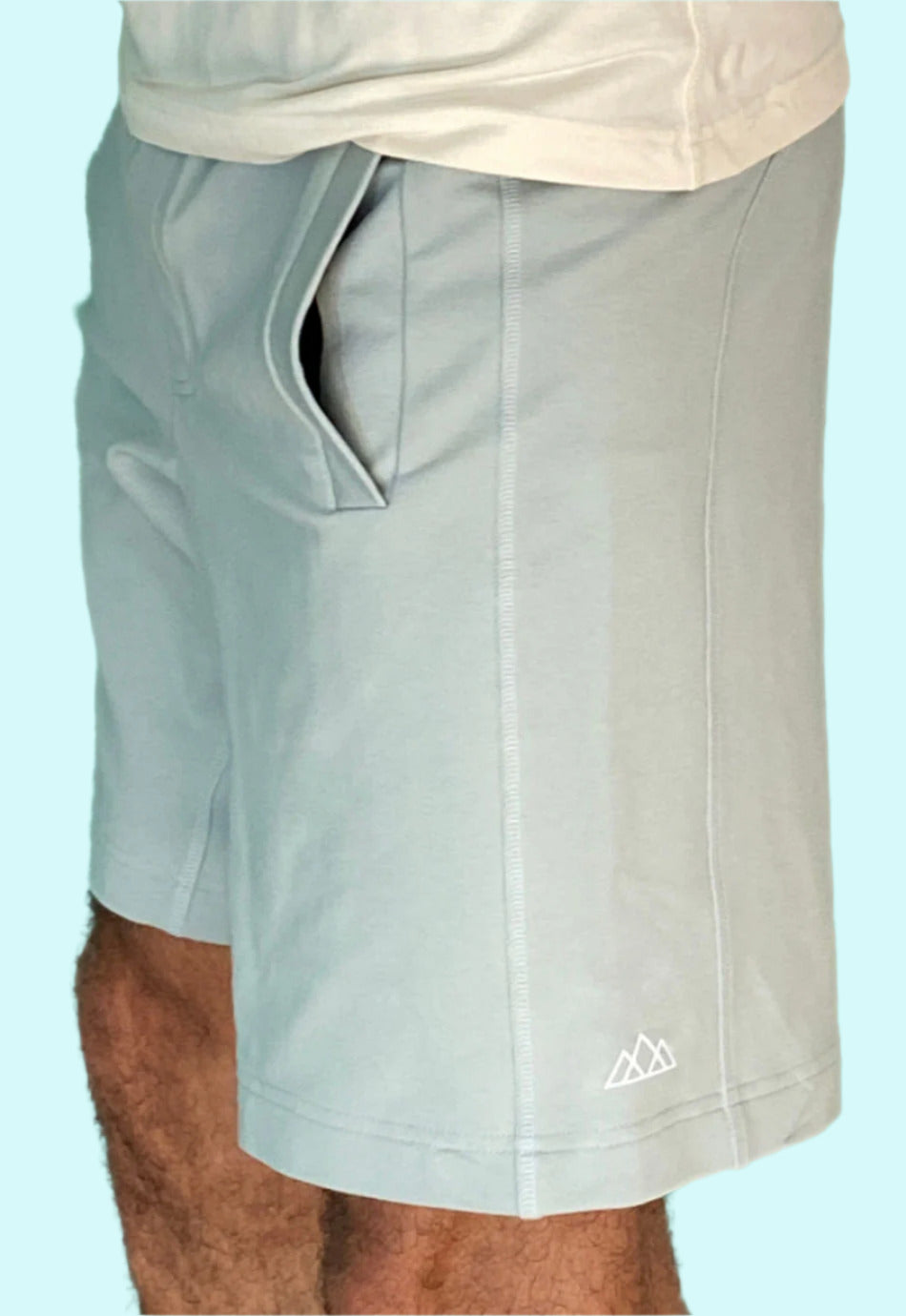 Linke Seitenansicht der M23 Zane Shorts in Salbei aus nachhaltiger Bio-Baumwolle – umweltfreundliche Herrenshorts mit Seitentasche und Logo-Print