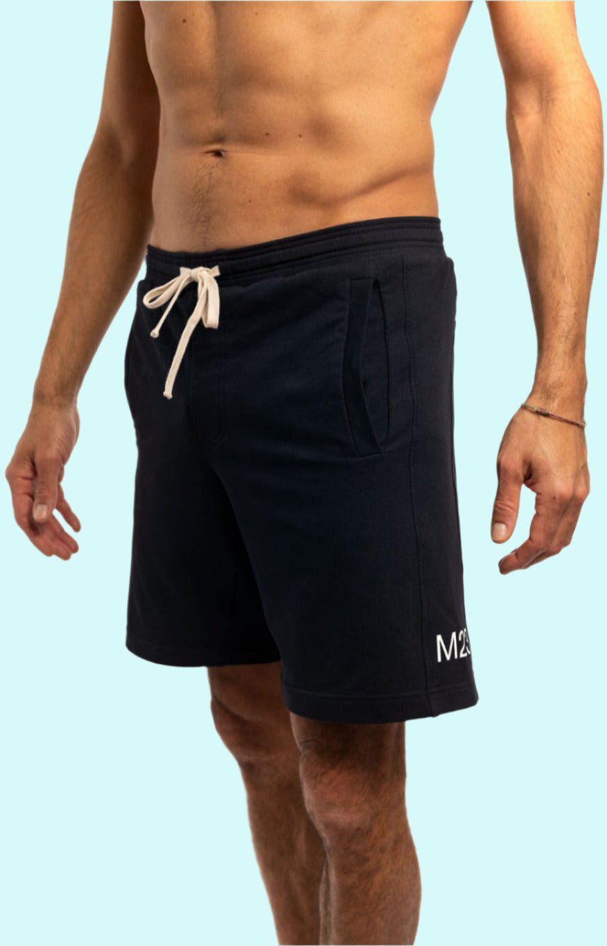 Schräg-vordere rechte Ansicht der M23 Zane Shorts in Salute-Marineblau aus nachhaltiger Bio-Baumwolle – umweltfreundliche Herrenshorts mit Kordelzug und M23-Logo